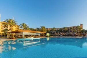 Una piscina al aire libre, sombrillas, sillones reclinables de piscina