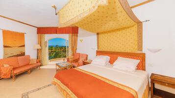 Une chambre d’hôtel avec un grand lit, un canapé, un fauteuil et une vue sur l’extérieur.