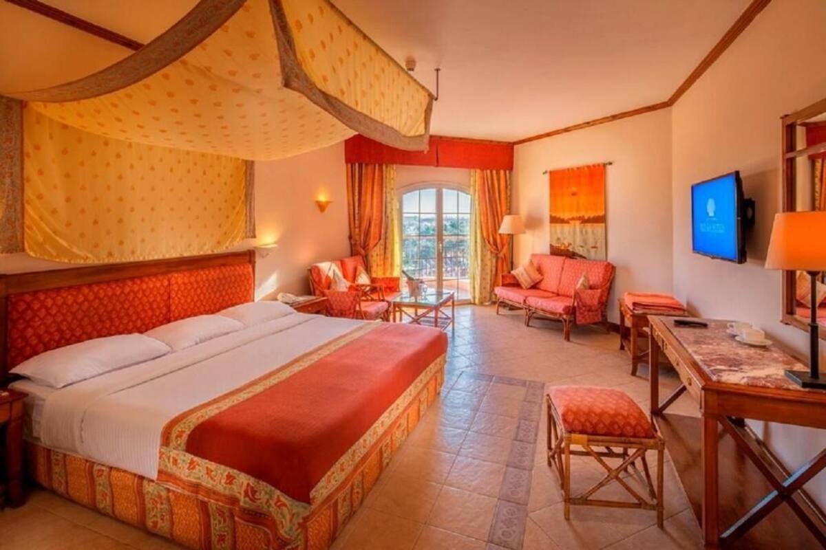A hotel room with a large bed, a desk, a chair, and a television.