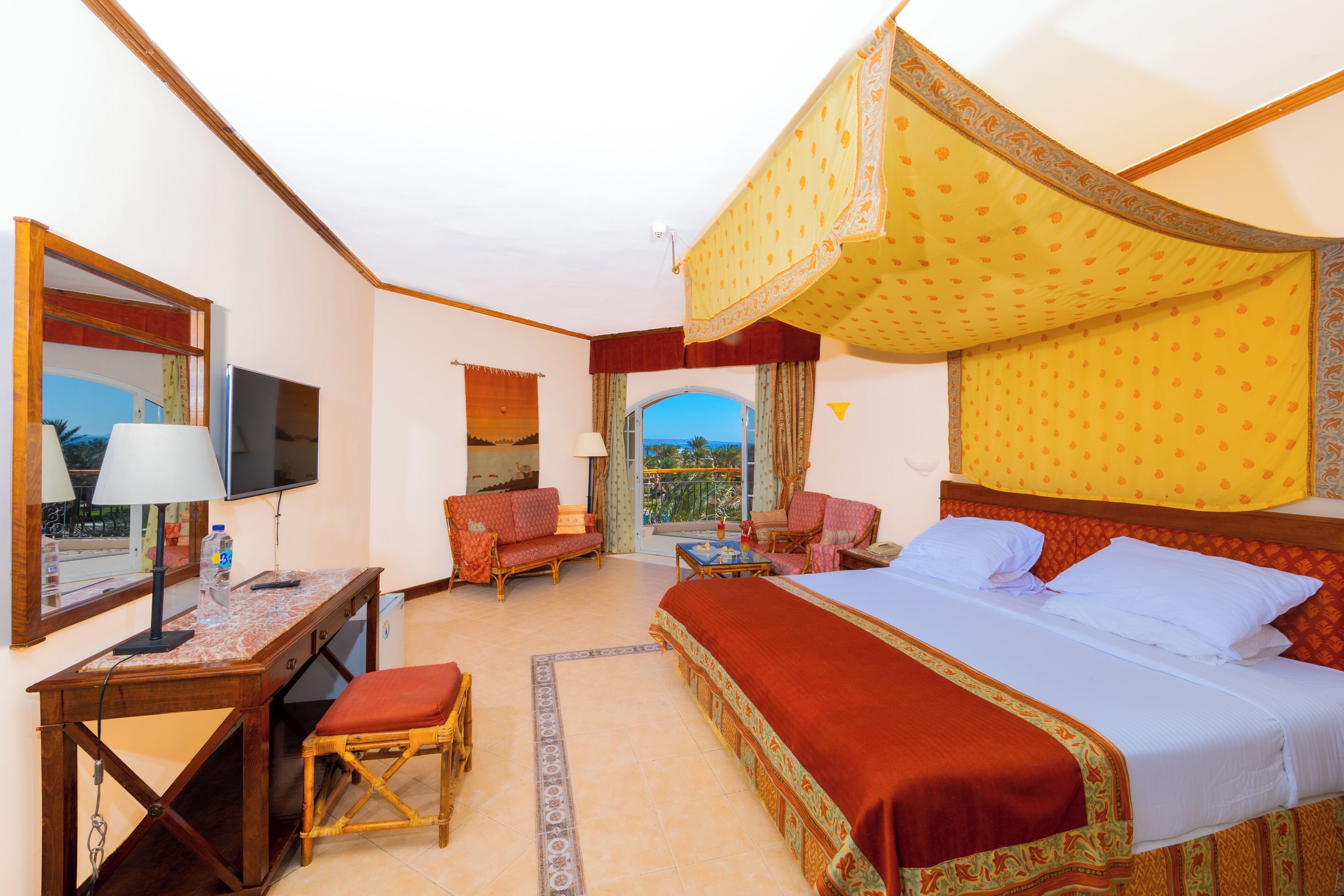A hotel room with a bed, desk, chair, and a television.