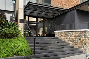 A modern building with a stone facade, a metal staircase, and a glass entrance. - The Signature 116 (Cape Town)