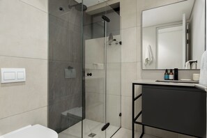 A modern bathroom with a glass-enclosed shower, a white sink, and a mirror above the sink. - The Signature 116 (Cape Town)
