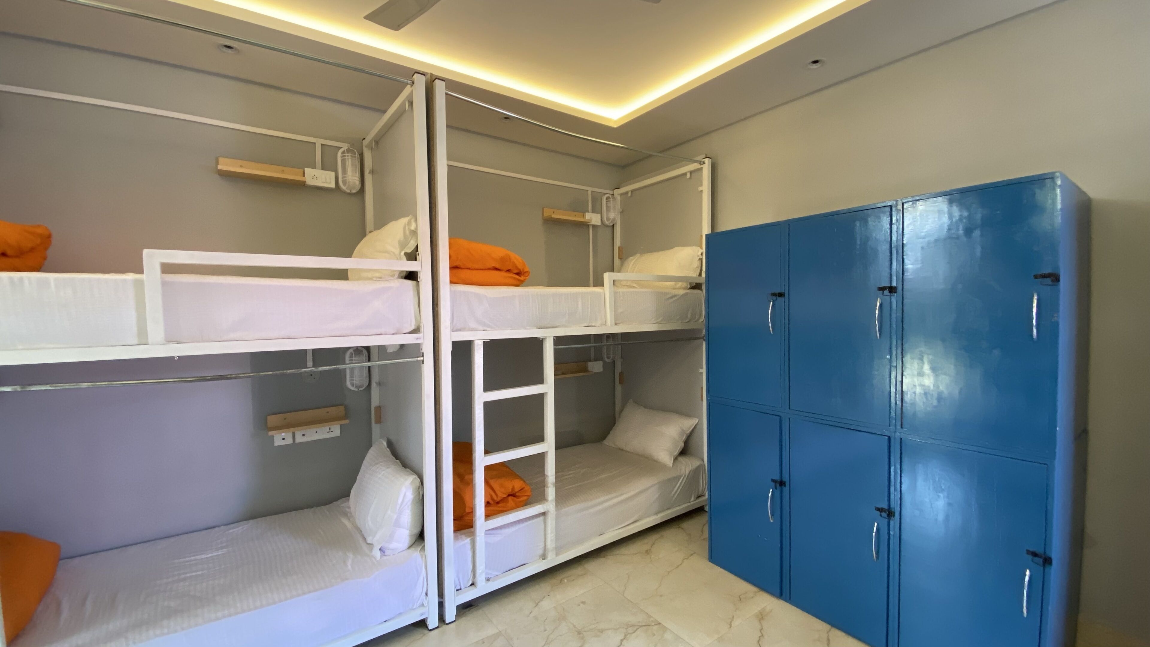 A bunk bed room with a blue wardrobe and a small shelf with a light fixture.