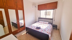Ein Schlafzimmer mit Bett, Kleiderschrank, Spiegel und Fenster.