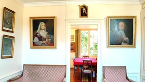 Een kamer met twee gestoffeerde banken, een eettafel met stoelen en diverse kunstwerken in lijsten aan de muren.