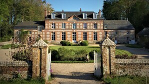 Een groot, historisch stenen gebouw met een symmetrische gevel, meerdere ramen en een goed onderhouden tuin.