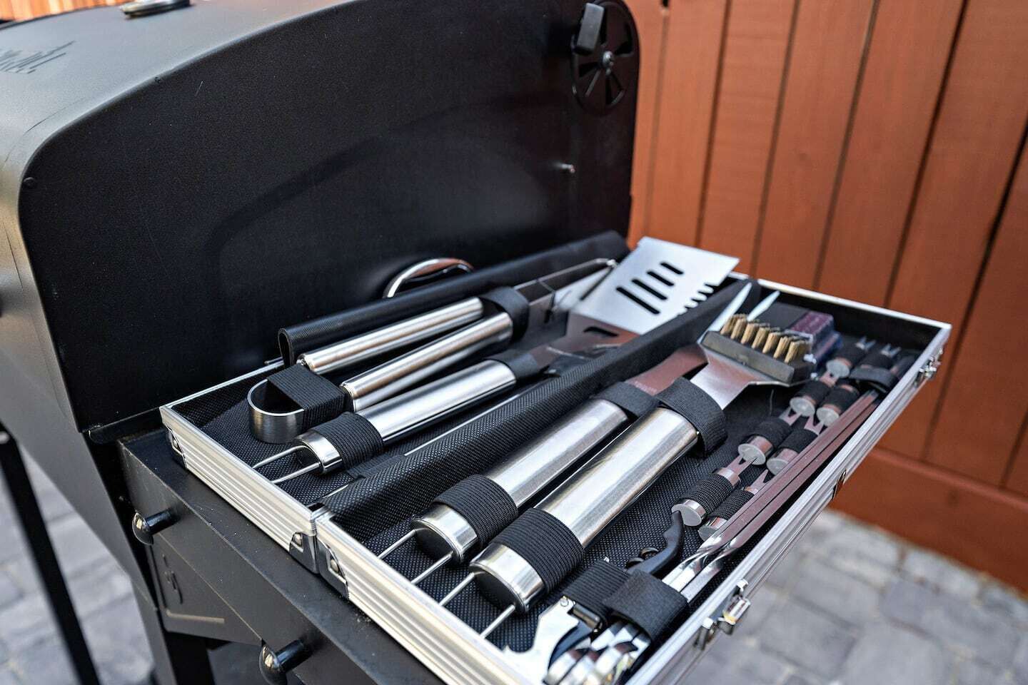 Ein Grill mit einer Werkzeugkiste, die verschiedene Grillutensilien beinhaltet.