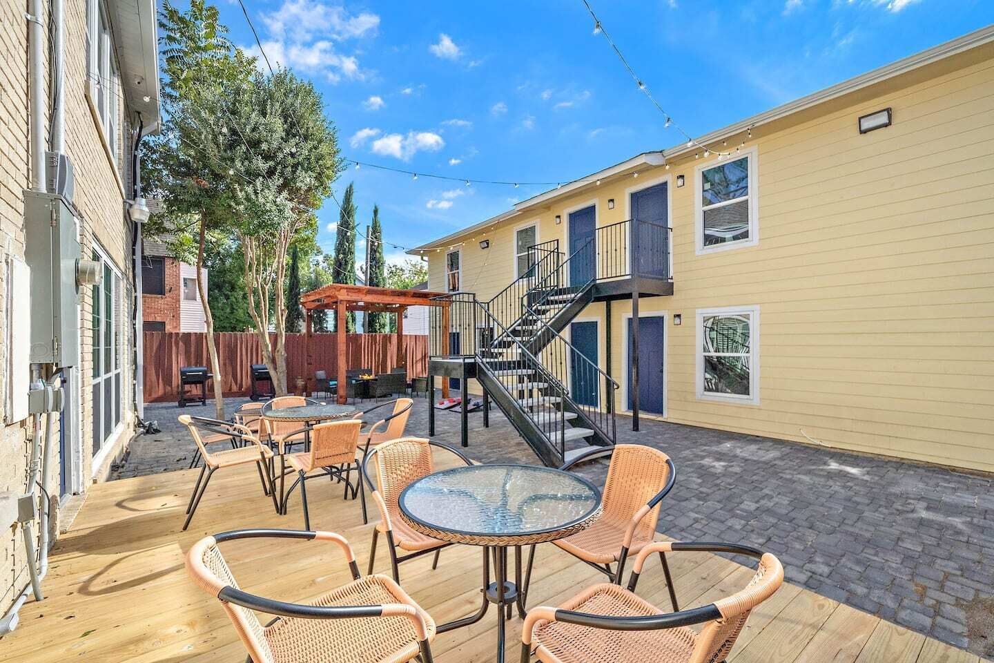 Une terrasse extérieure aménagée avec des meubles en osier, une table en verre et une plateforme en bois.