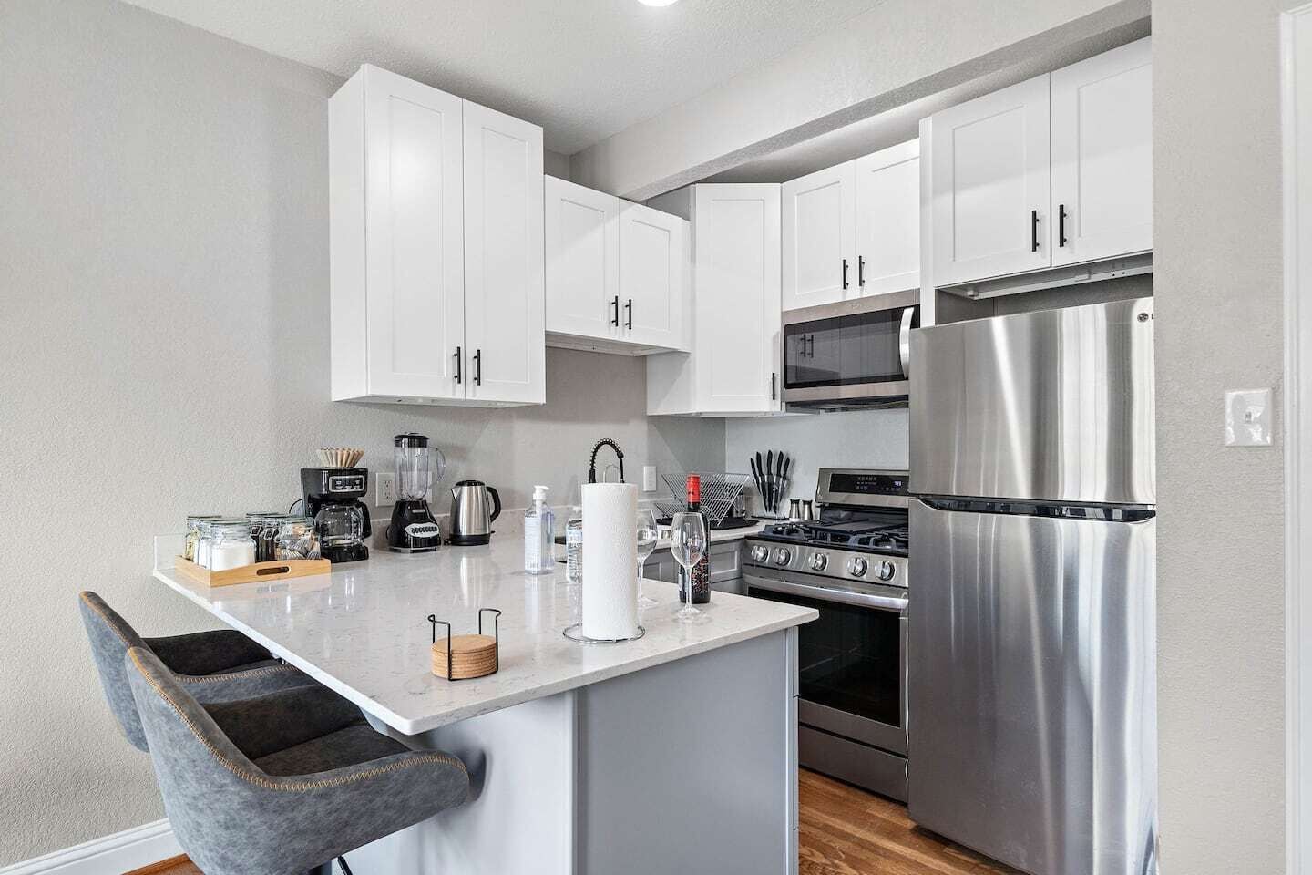 A modern kitchen with white cabinets, stainless steel appliances, and a central island.