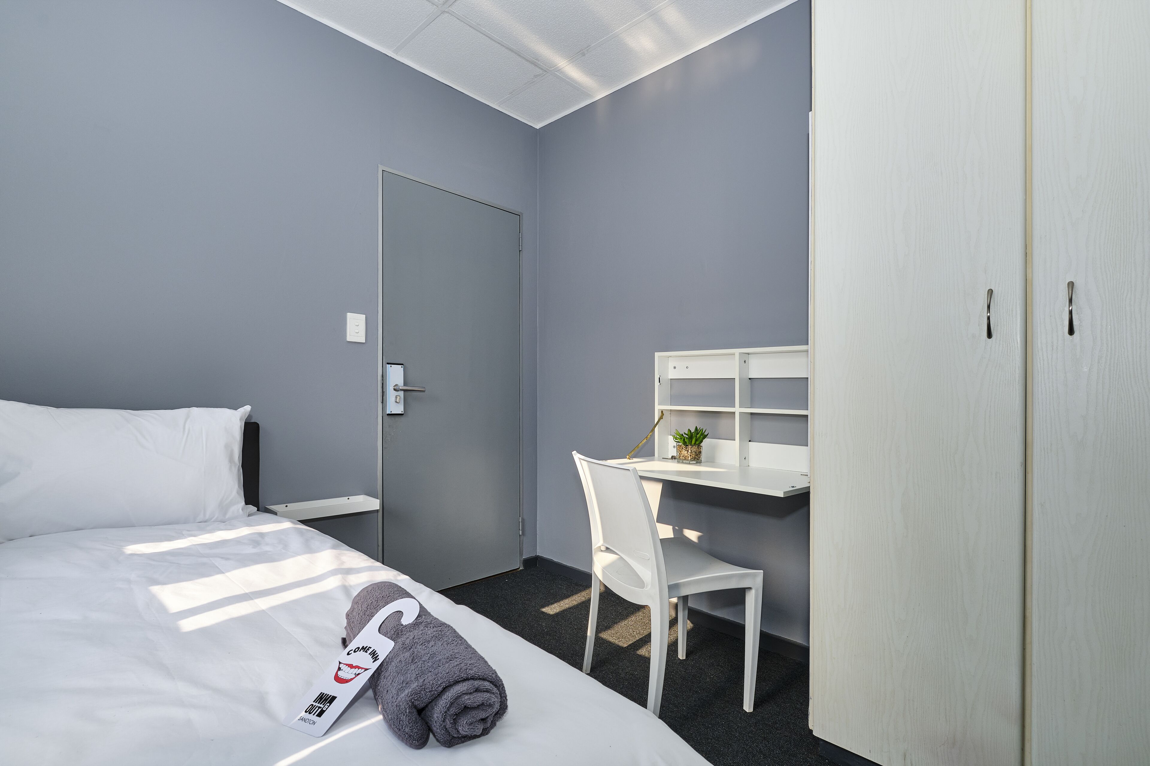 Une chambre d’hôtel comprenant un lit, un bureau, une chaise et une armoire.