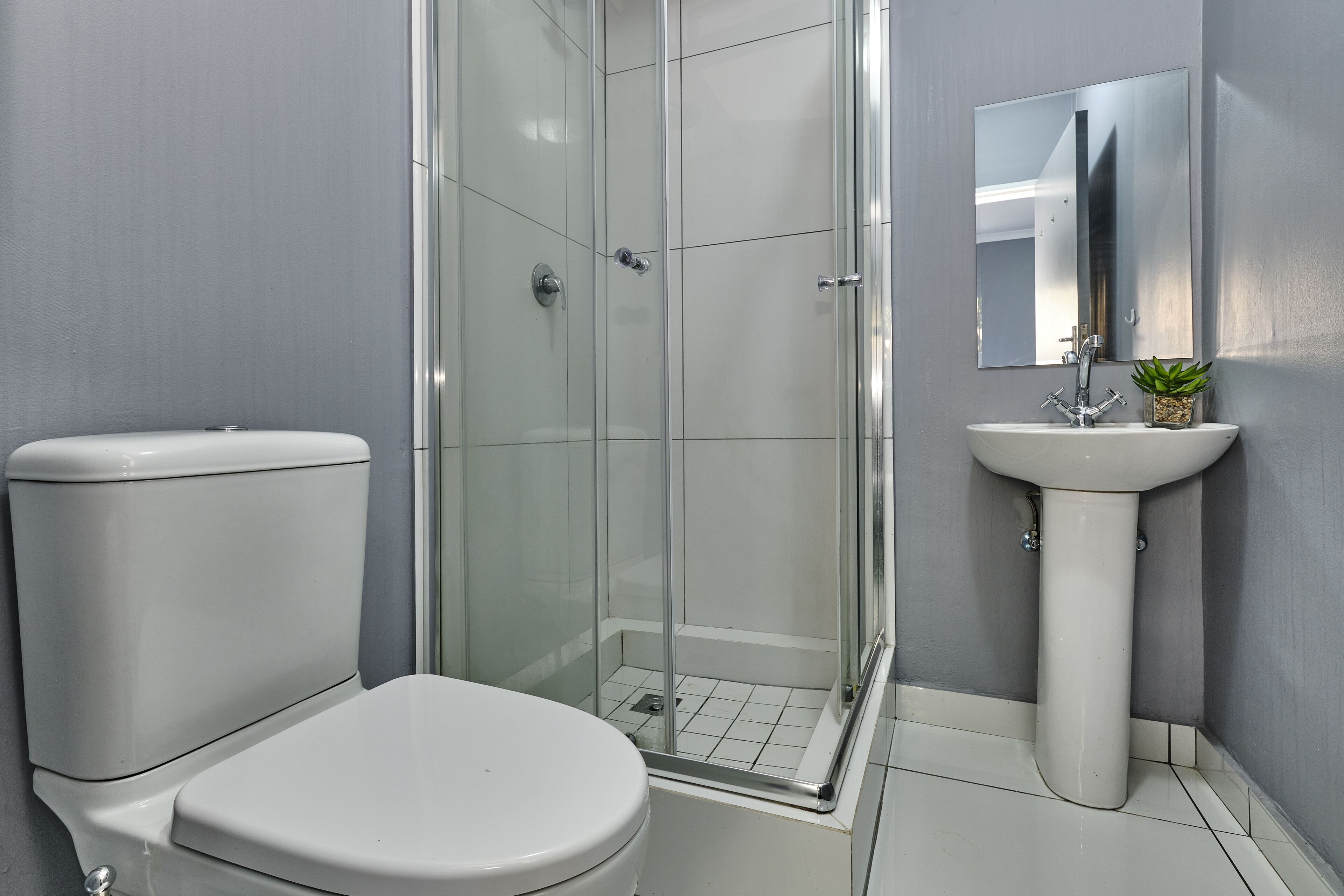 A bathroom with a toilet, a sink, and a glass-enclosed shower.