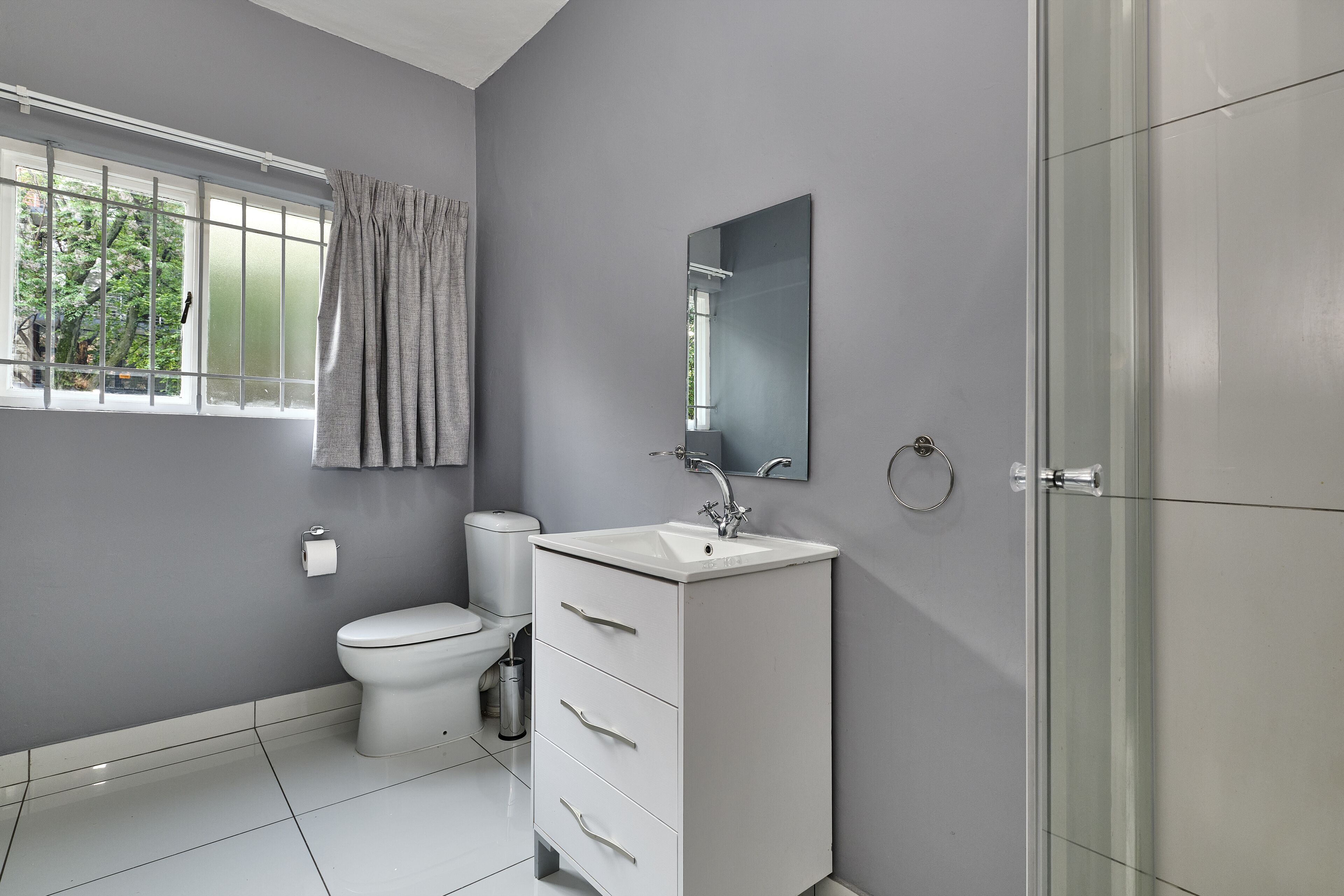 A modern bathroom with a toilet, sink, and mirror.