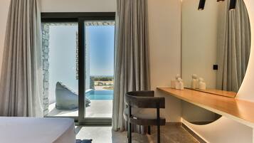A modern bedroom with a large sliding glass door leading to a pool, a wooden vanity, and a curved mirror.