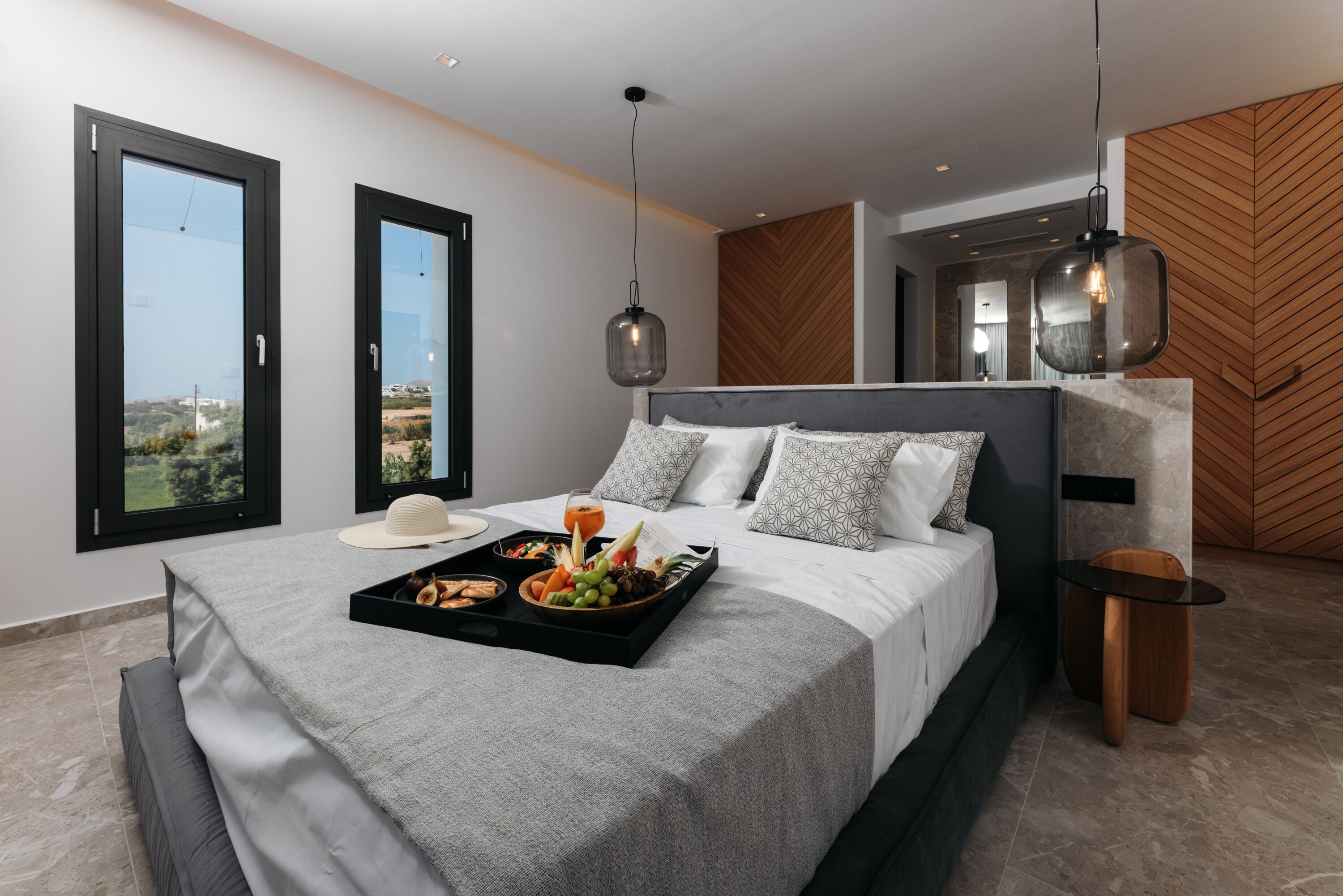 A modern bedroom with a bed, bedside tables, and a tray of breakfast items.