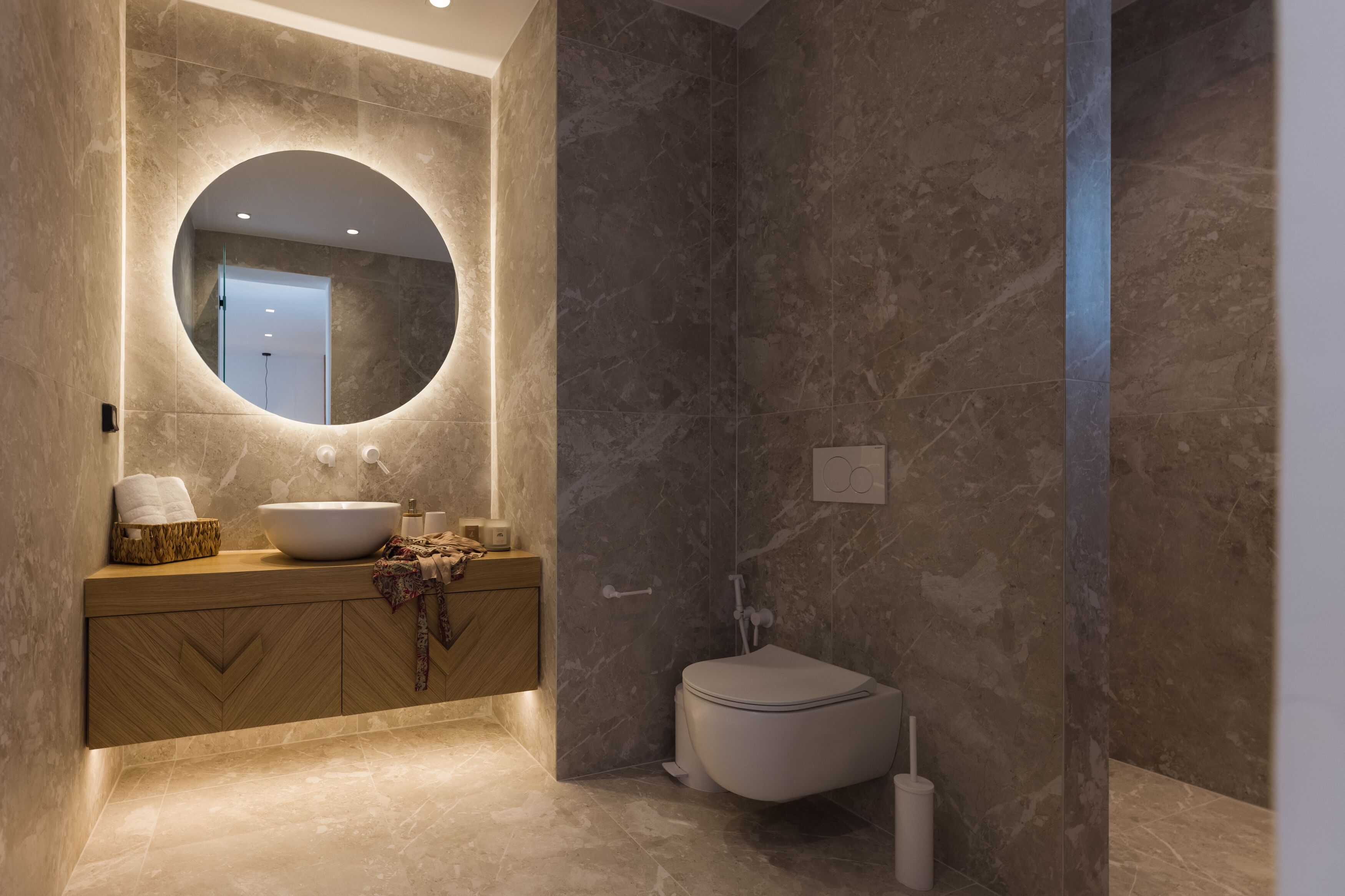Un baño moderno con un espejo redondo, un lavabo y un inodoro.