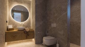 Un baño moderno con un espejo redondo, un lavabo y un inodoro.