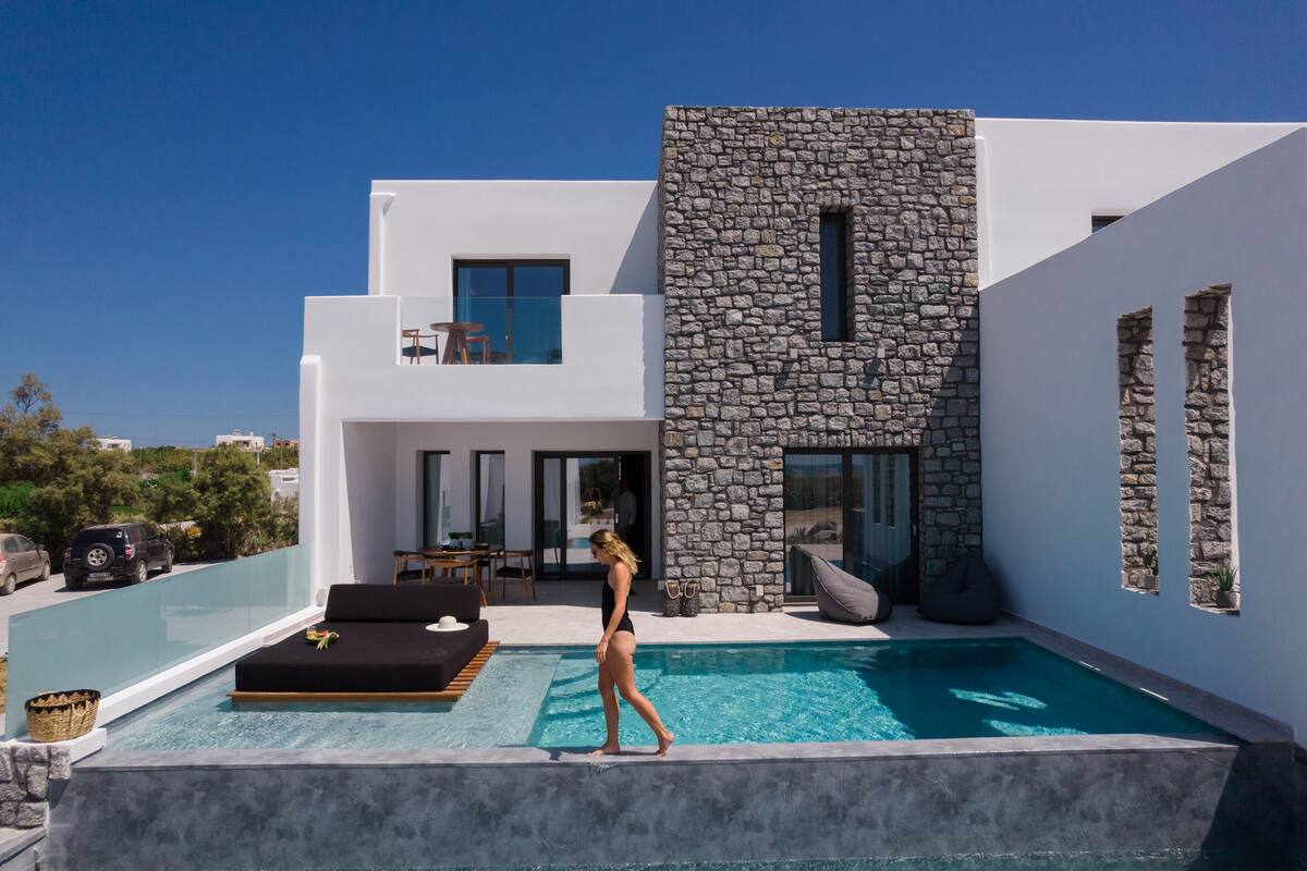 Eine moderne Villa mit Pool, Naturstein-Fassade und Sitzgelegenheit im Freien.