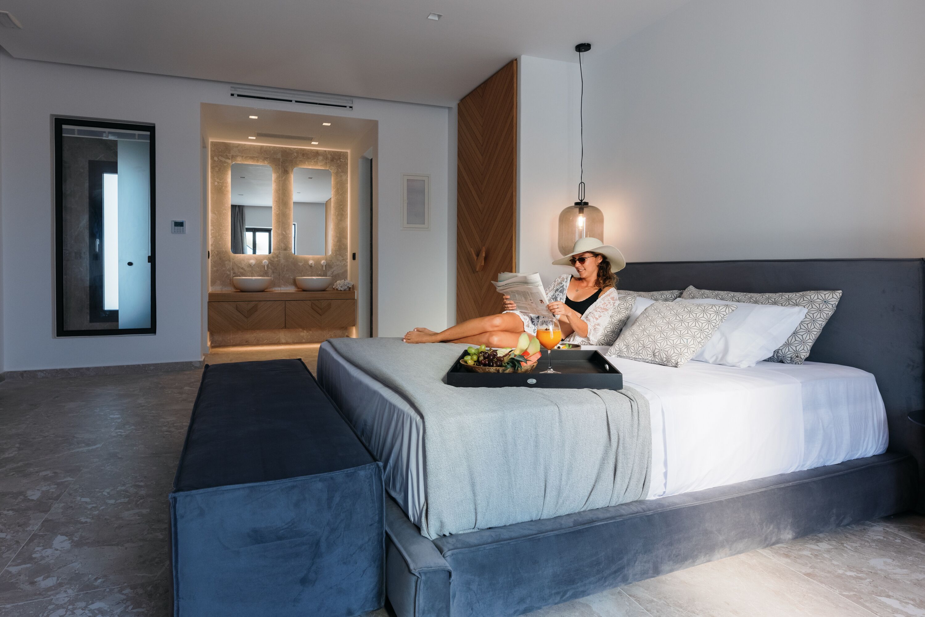 A modern bedroom with a large bed, bedside table, and a reading area.