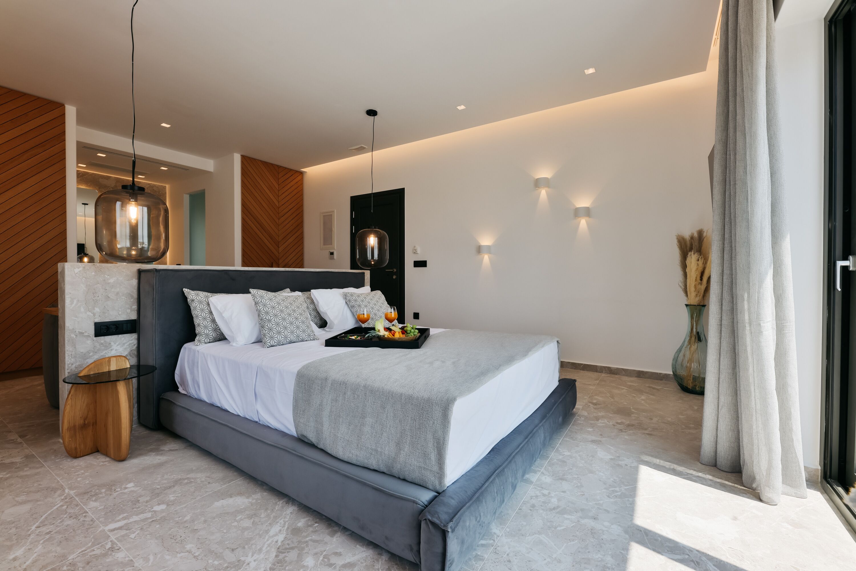 Een moderne slaapkamer met een groot bed, nachtkastjes en een bijzetmeubel.