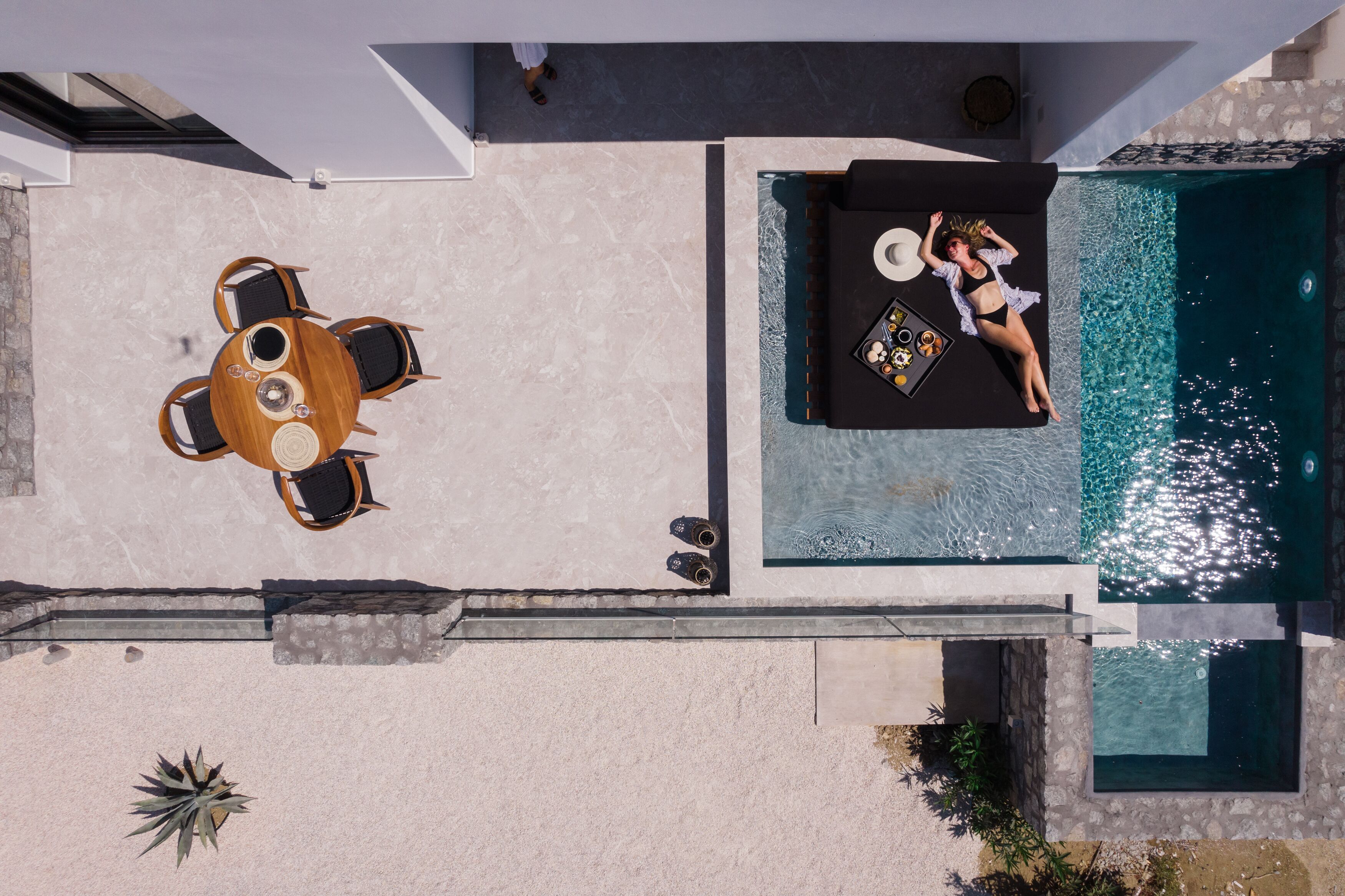 A rooftop pool area with a lounge chair and a dining table.