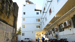 A narrow street with a white building labeled "HOTEL VELAN" and parked motorcycles. - Hotel Velan International  (Krishnagiri)