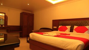 A hotel room with a large bed, a wooden wardrobe, and a desk. - Hotel Velan International  (Krishnagiri)