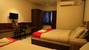 A hotel room with two beds, a desk, a chair, and a television. - Hotel Velan International  (Krishnagiri)