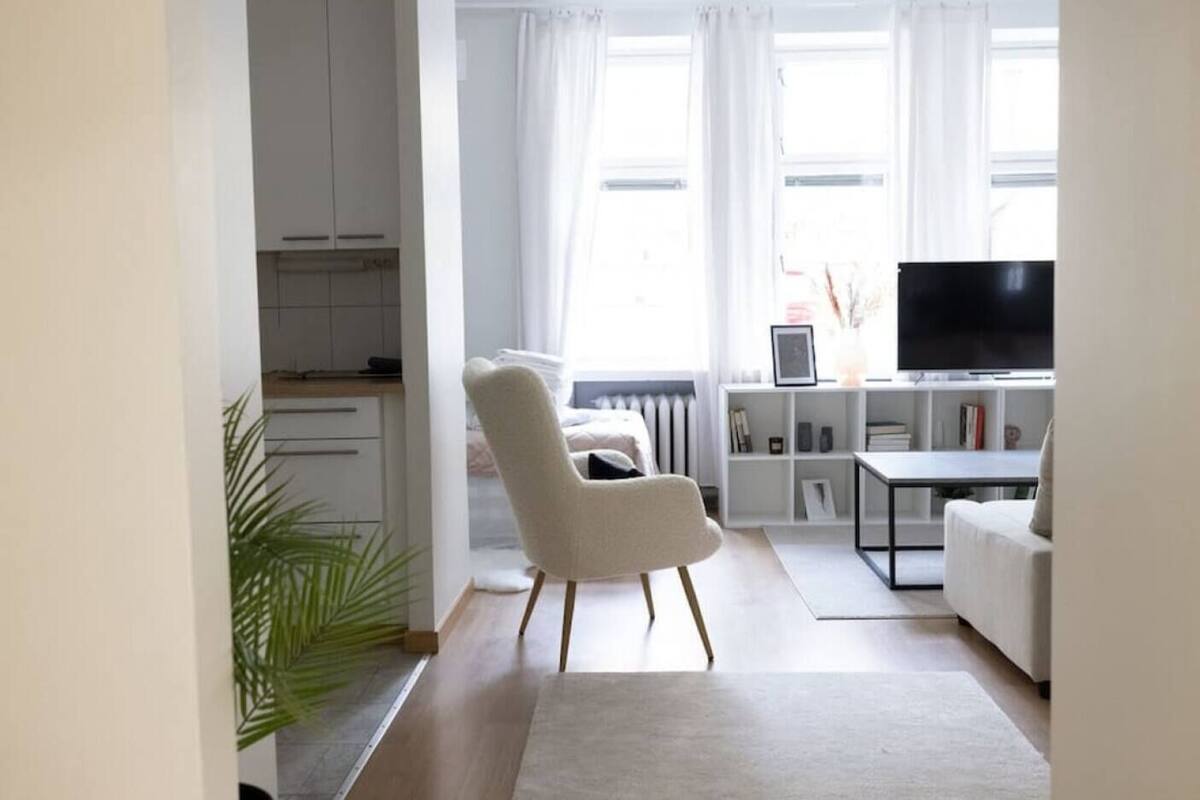 Uma sala de estar moderna com um sofá, uma televisão e uma estante de livros.