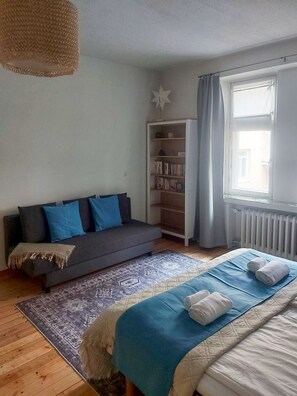 Une chambre à coucher avec un lit, un canapé, une bibliothèque et une fenêtre.