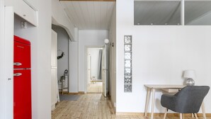 A modern room with a wooden floor, a red refrigerator, a grey chair, and a white desk with a lamp. - 2ndhomes Central 85m2 2BR Apartment (Helsinki)