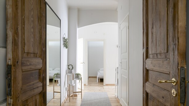 A hallway with wooden doors leading to a bedroom with a bed and a bedside table. - 2ndhomes Central 85m2 2BR Apartment (Helsinki)