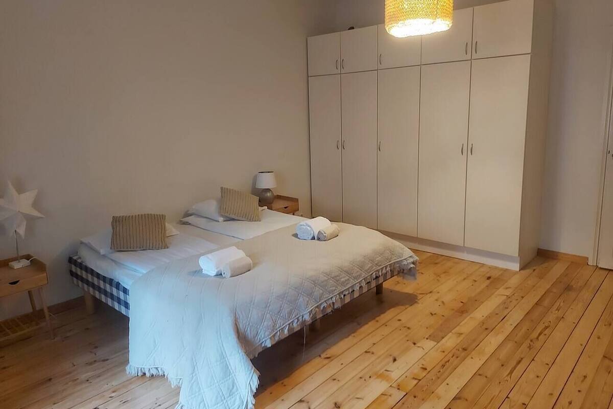 Une chambre à coucher comprenant un lit, une table de chevet, une lampe, une armoire et un luminaire suspendu.