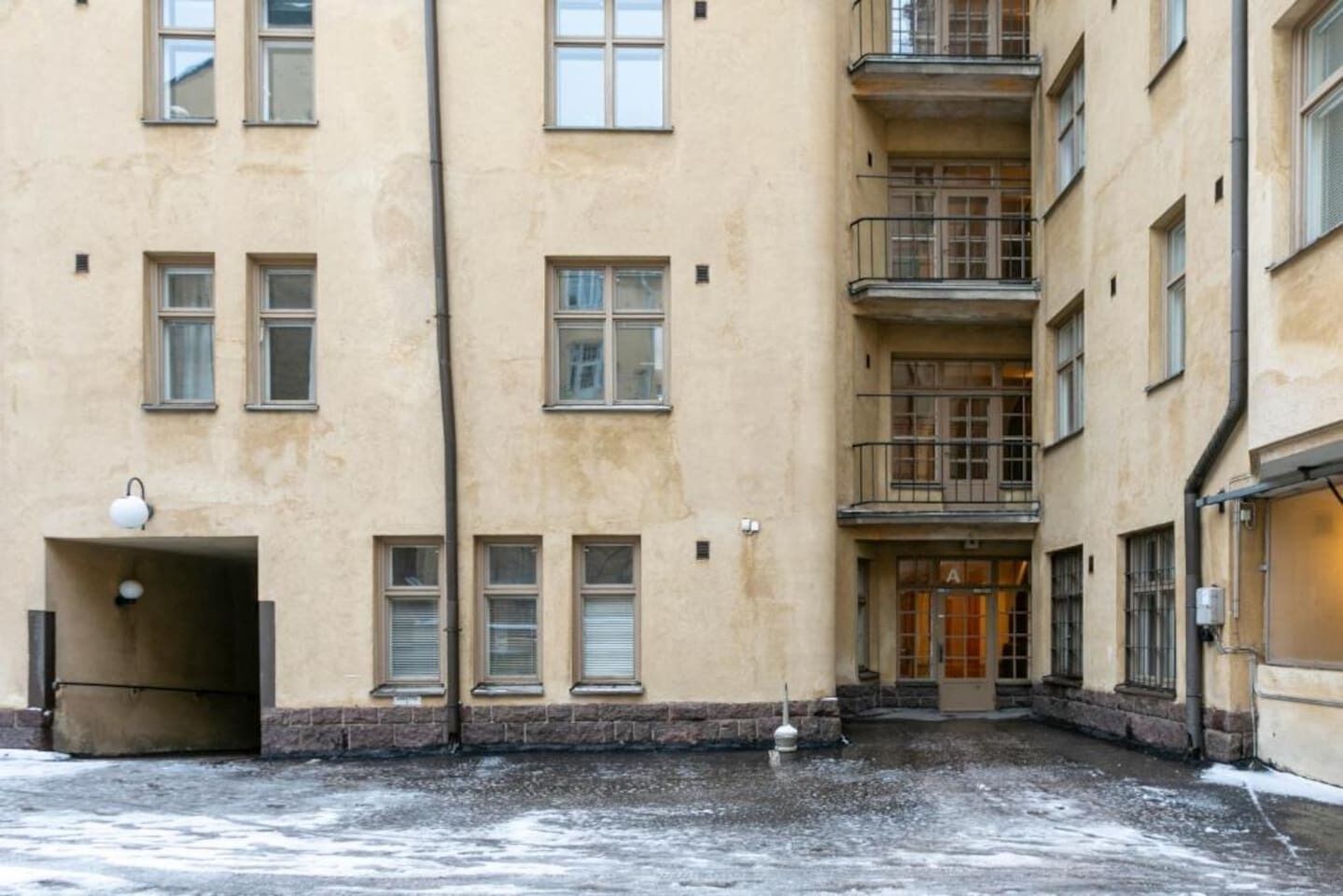 Un immeuble à plusieurs étages doté d’une cour intérieure, d’un escalier et d’une porte sur laquelle est apposée une enseigne.