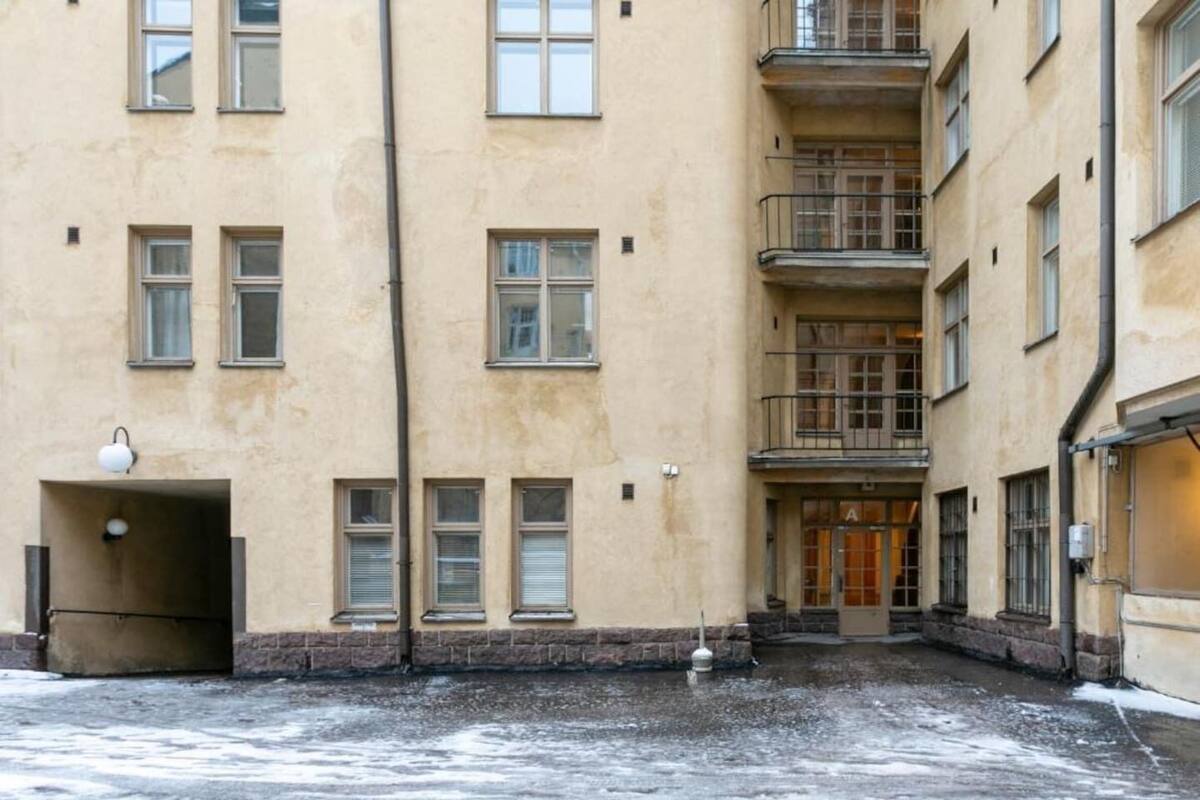 Ein mehrstöckiges Gebäude mit Innenhof, Treppe und einer Tür mit einem Schild.