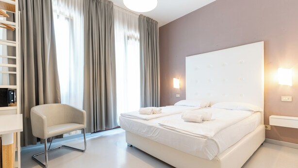 Une chambre d’hôtel moderne avec un grand lit, une chaise et un bureau.