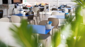 Un espace repas moderne, avec des tables et des chaises, dont certaines ont des plateaux bleus.