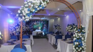 Un saló de banquetes amb taules rodones, caires blaus i tovallons blancs.