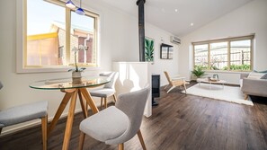 A modern living room with a glass dining table, grey upholstered chairs, a sofa, and a fireplace. - Sunshine Retreat Villa 4 (Cowes)