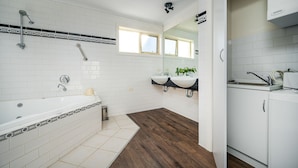 Une salle de bain moderne avec une baignoire, deux lavabos, un miroir et une fenêtre.