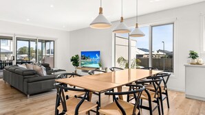 Ein modernes Wohnzimmer mit einem grauen Sofa, einem Holzesstisch mit Stühlen und einem Fernseher an der Wand.