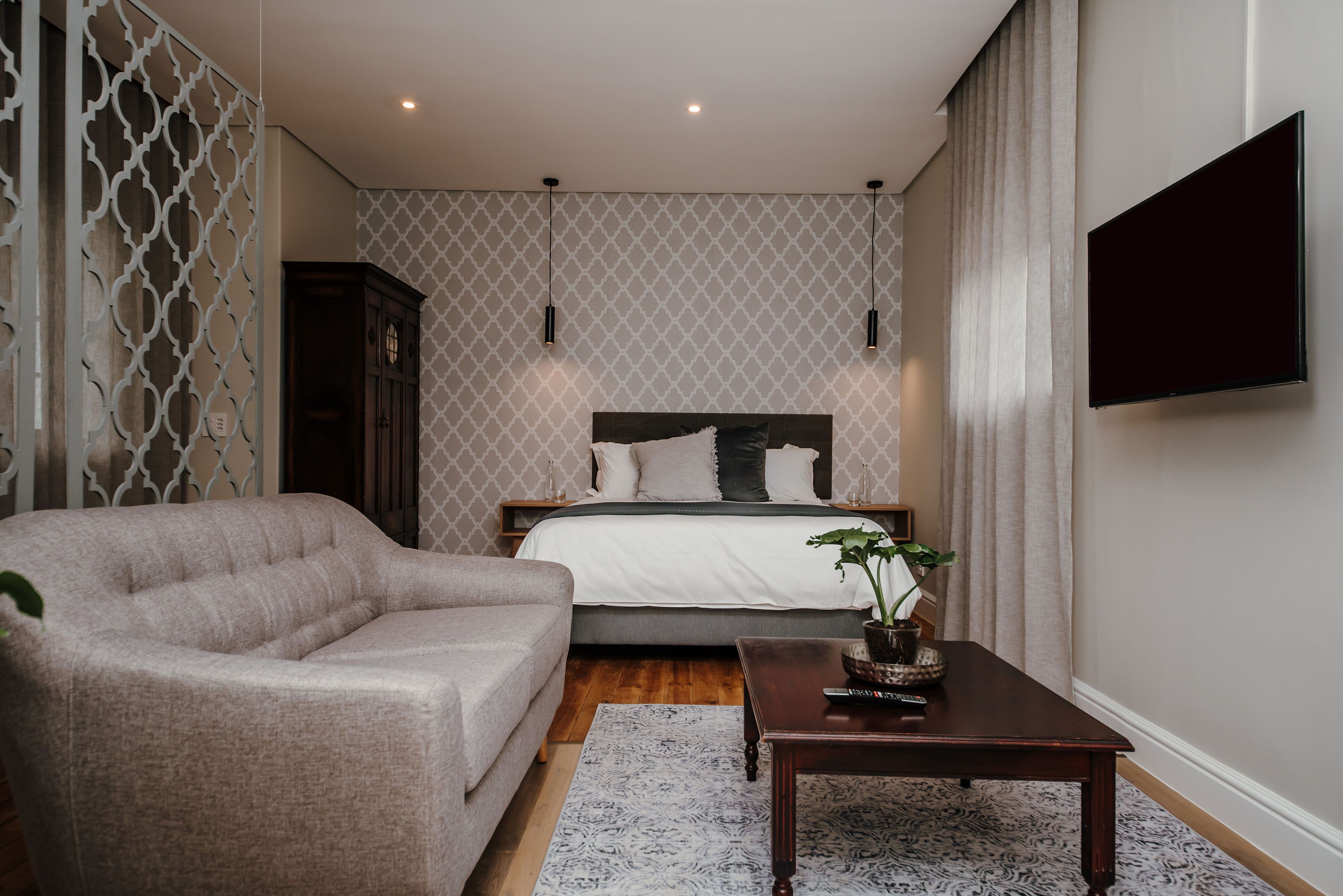 A bedroom with a bed, a sofa, a coffee table, and a TV.