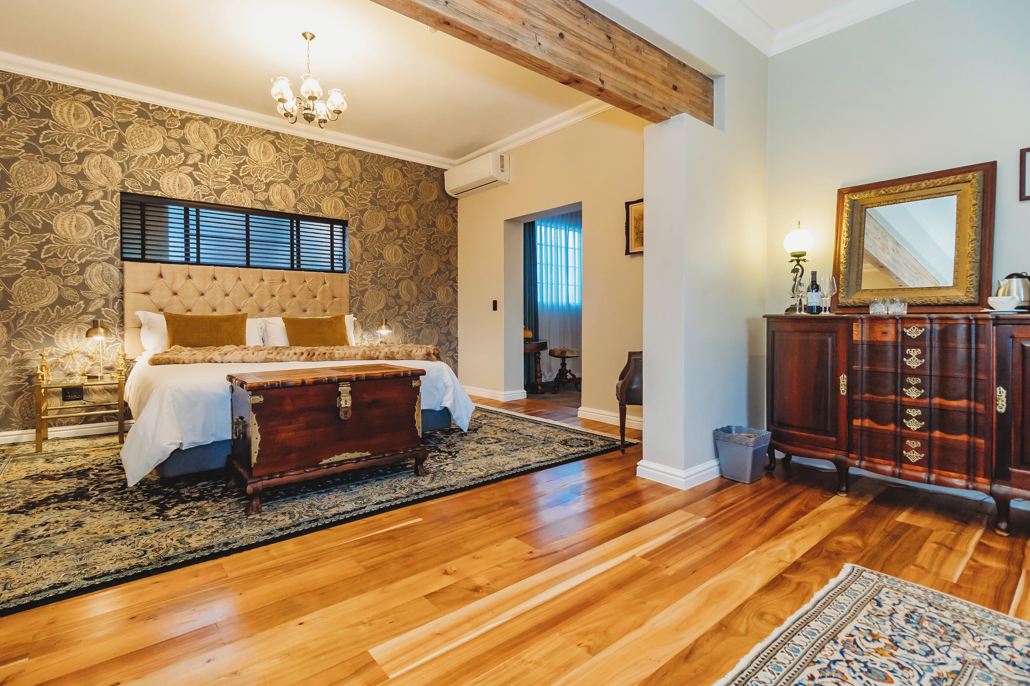A bedroom with a large bed, a wooden dresser, and a chandelier.