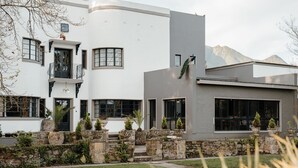 A modern two-story house with a stone facade, large windows, and a landscaped front yard with potted plants. - The Hawthorn Boutique Hotel (George)