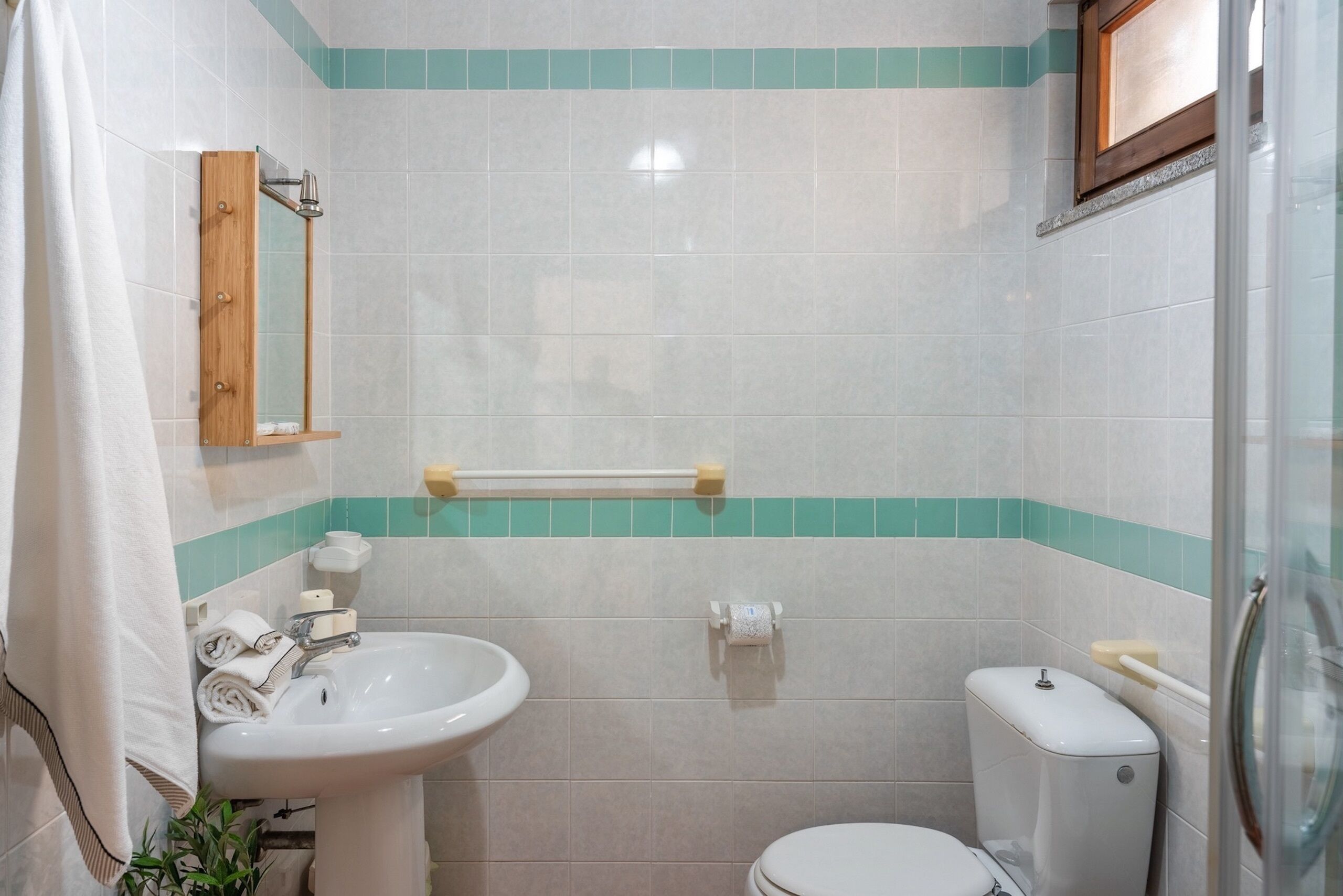 A bathroom with a sink, toilet, and a mirror.