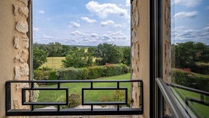 A view from a balcony with stone walls and a metal railing, overlooking a green landscape with trees and a clear sky. - Spacious, comfortable stone farmhouse with swimming pool for 8 people in Uzès (GARRIGUES STE EULALIE)