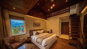 Un dormitorio espacioso con una cama grande, techo de madera, vista a las montañas y una escalera.
