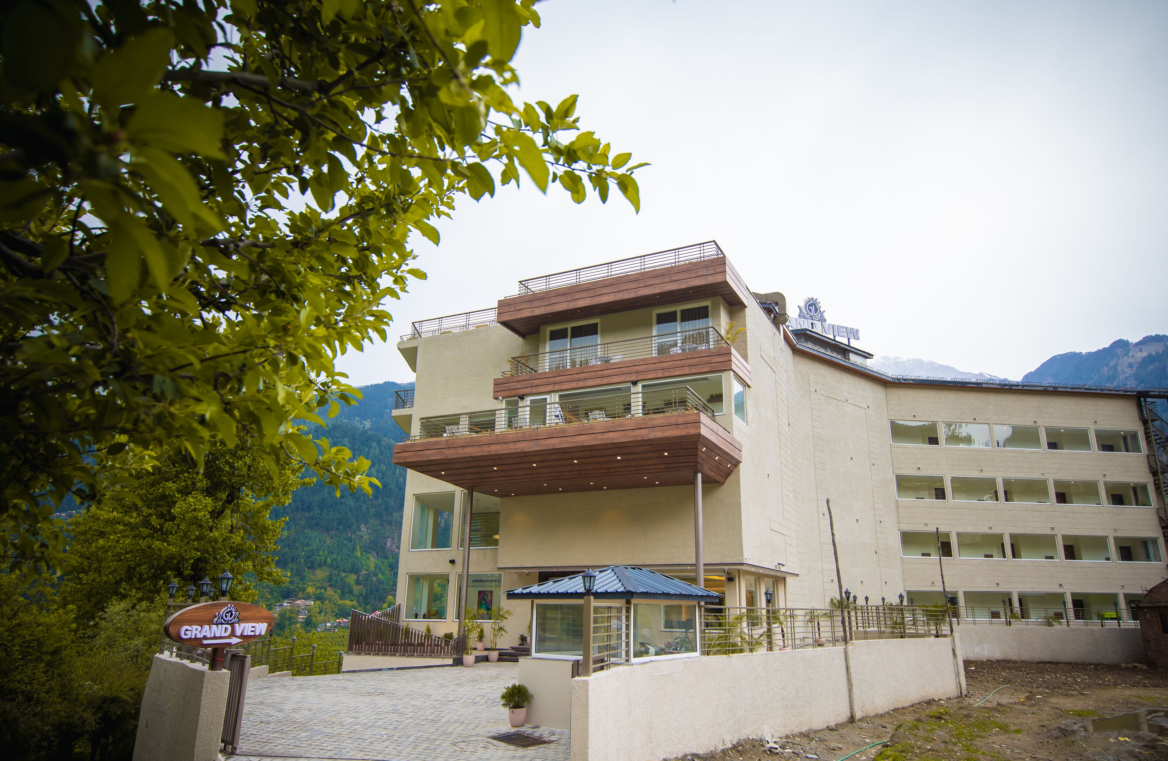 A multi-story hotel with balconies, a sign reading "Grand View," and a mountainous backdrop.