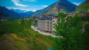 Un hotel de varios pisos, con un patio central y montañas al fondo.