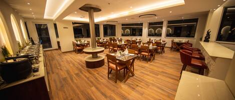 Un restaurante espacioso con suelo de madera, varias mesas y sillas.
