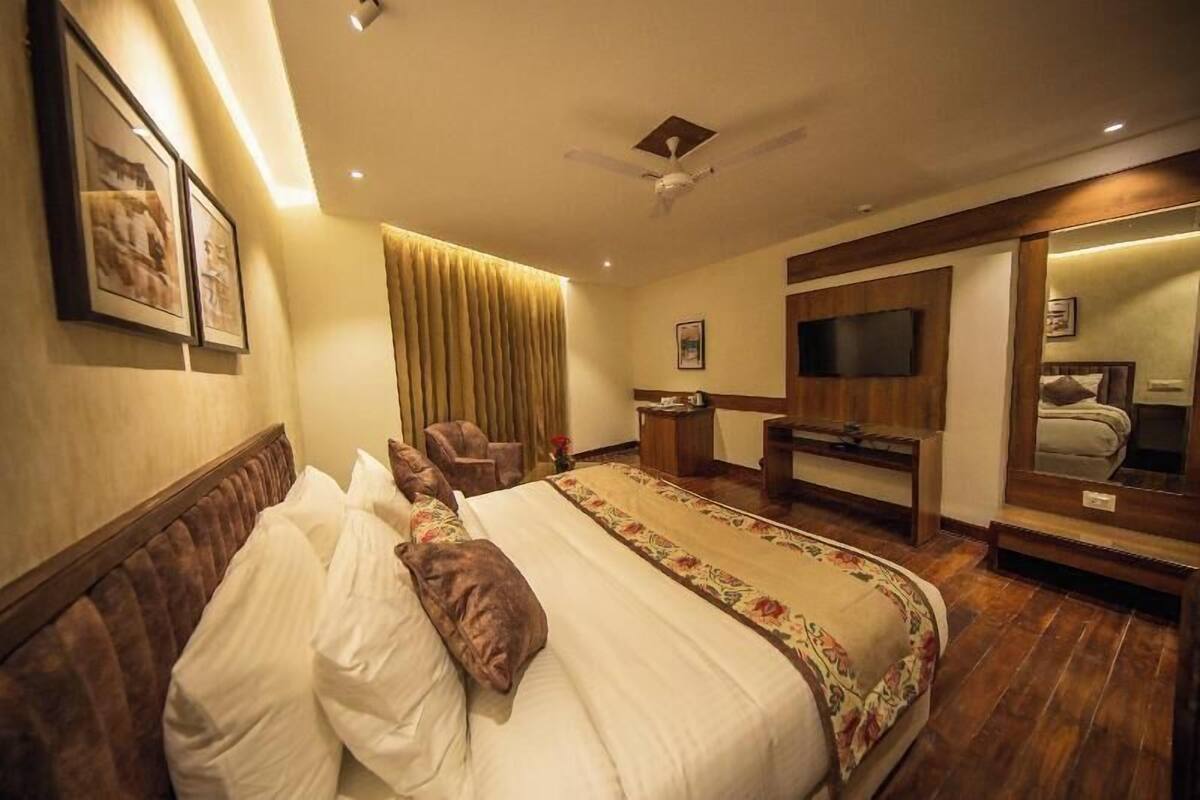 A hotel room with a bed, a desk, a chair, a television, and a mirror.